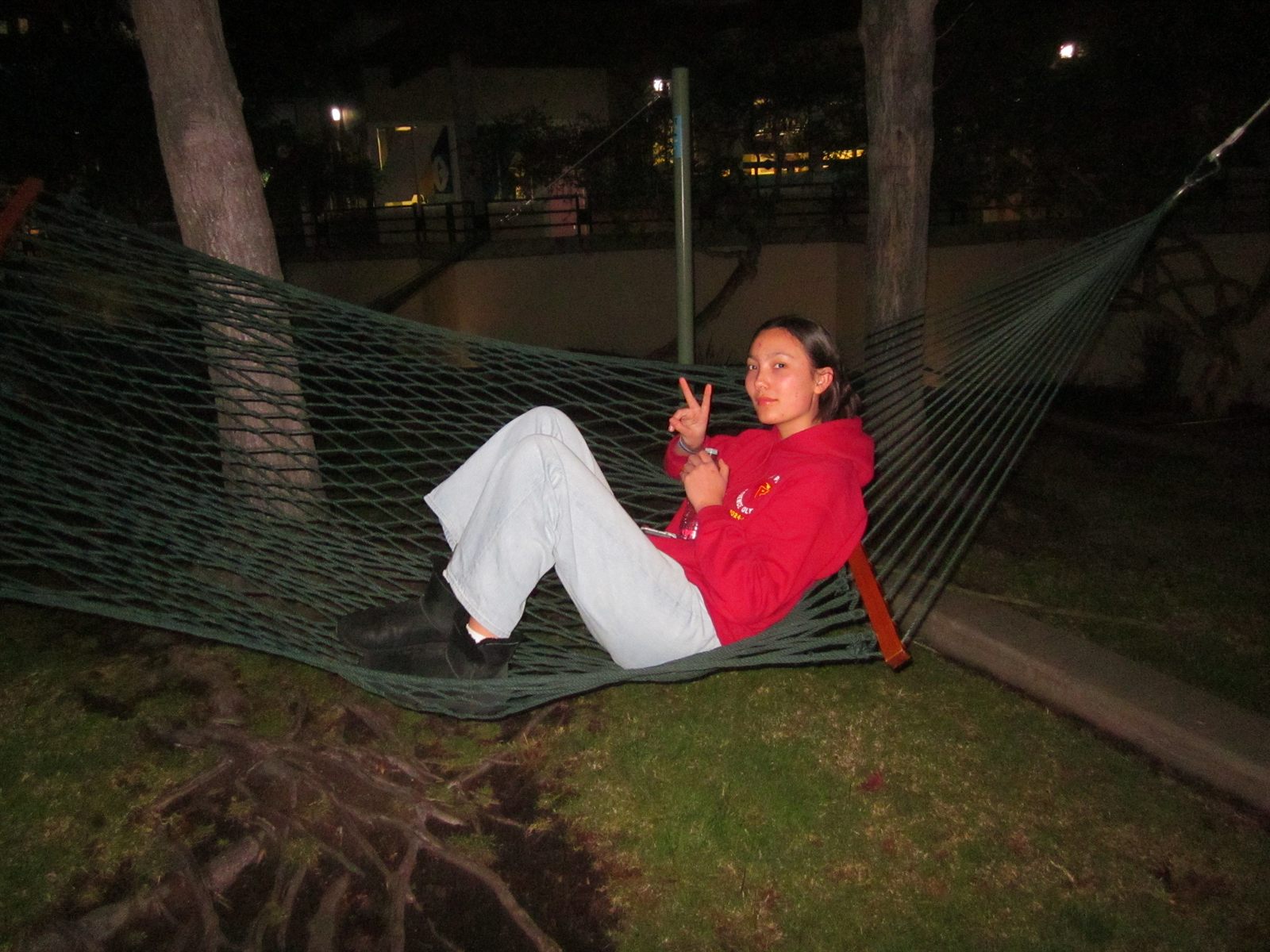 Vera Muller in a red Science Olympiad hoodie, resting in a hammock on campus