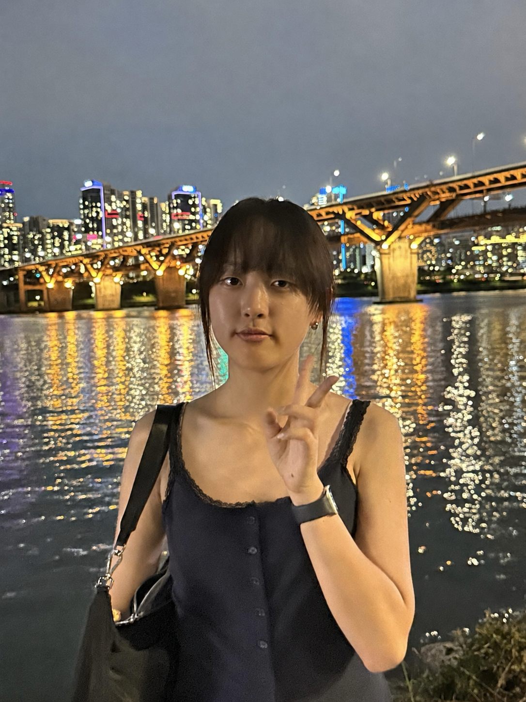 Stella Jeong on a riverside walkway at night, city lights behind her